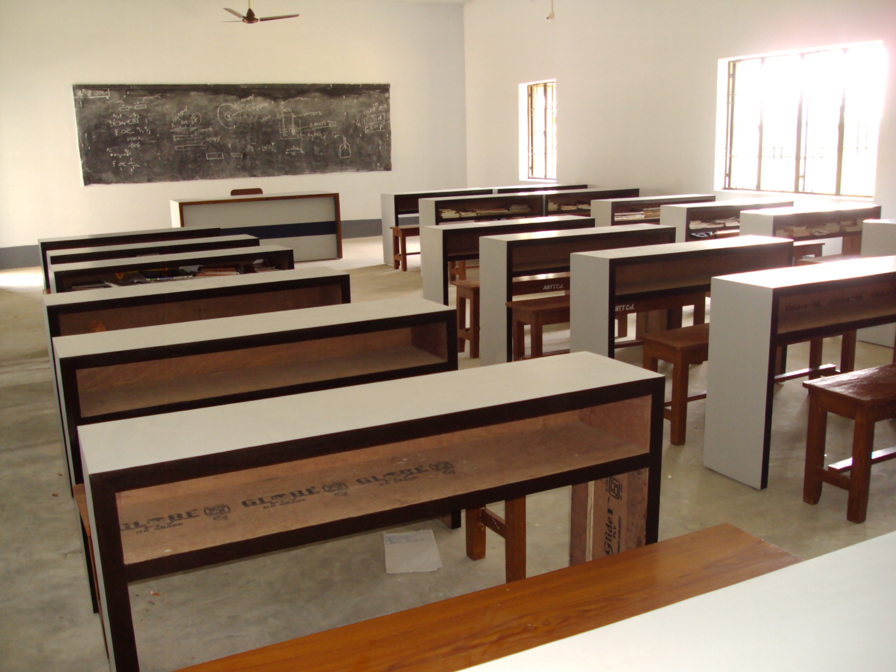 Classroom with desks arranged before a chalkboard of physics notes